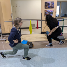 two women doing lunges indoors.