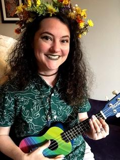 Anna Goldberg with flowers on her head playing a colorful ukelele