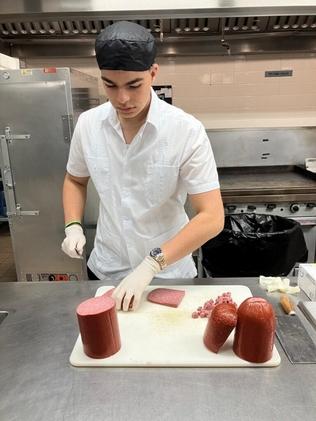 Sebastian slices meat in an industrial kitchen