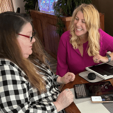 A woman tries out different readers and keyboards at a table with an Easterseals staff member