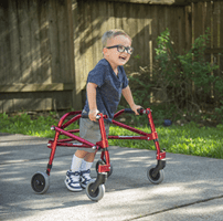 A young boy using a walker, smiling and laughing