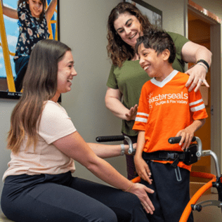 Jaxon with Easterseals staff, using a walker