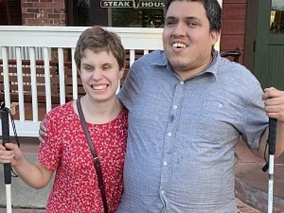 We are standing outside the restaurant. I’m wearing a sundress and he’s wearing a dress shirt with dress pants and dress shoes. We are standing side-by-side with an arm around each other and smiling. It was taken after dinner for our two year anniversary.