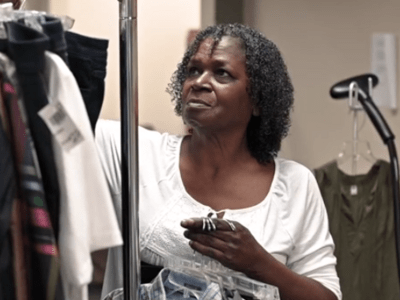 An older woman hanging up clothes on a rack 