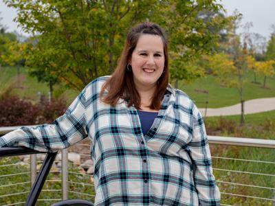 Sarah, relaxed and smiling, against a fence