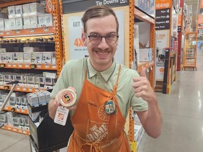 A man in a department store shows off badge celebrating 5 years working at Home Depot