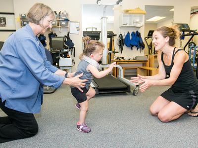 A young girl walks between two therapists