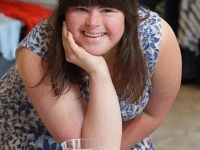 Collette Divitto smiling delightfully, leaning on a table with a tray full of cookies and a cup of milk