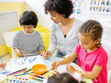 A woman in a classroom teaching two young children