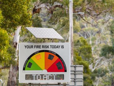 Solar powered fire danger status and bush fire risk sign installed on public road side showing high level on day