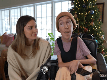 A man in a wheelchair and a woman talk by a Christmas Tree