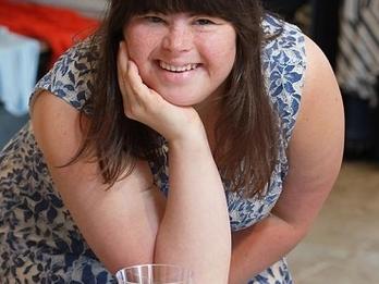 Collette Divitto smiling delightfully, leaning on a table with a tray full of cookies and a cup of milk