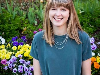 Kaelynn Partlow smiling in front of a field of tulips