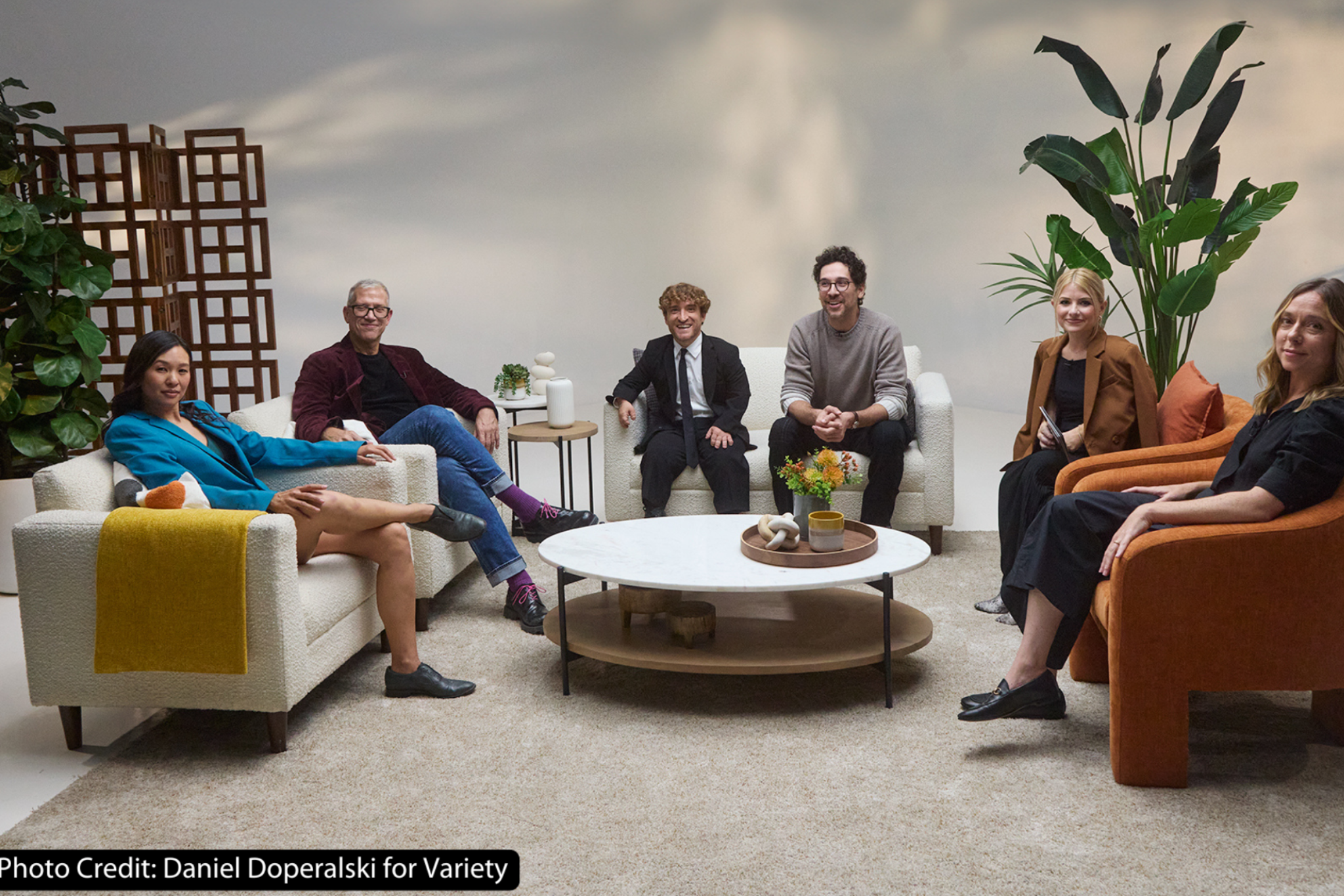 A group photo of six individuals sitting a living room setting.