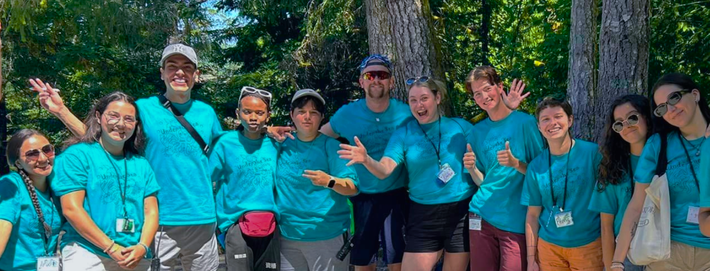 a group of camp employees smiling for a photo outside on a sunny day