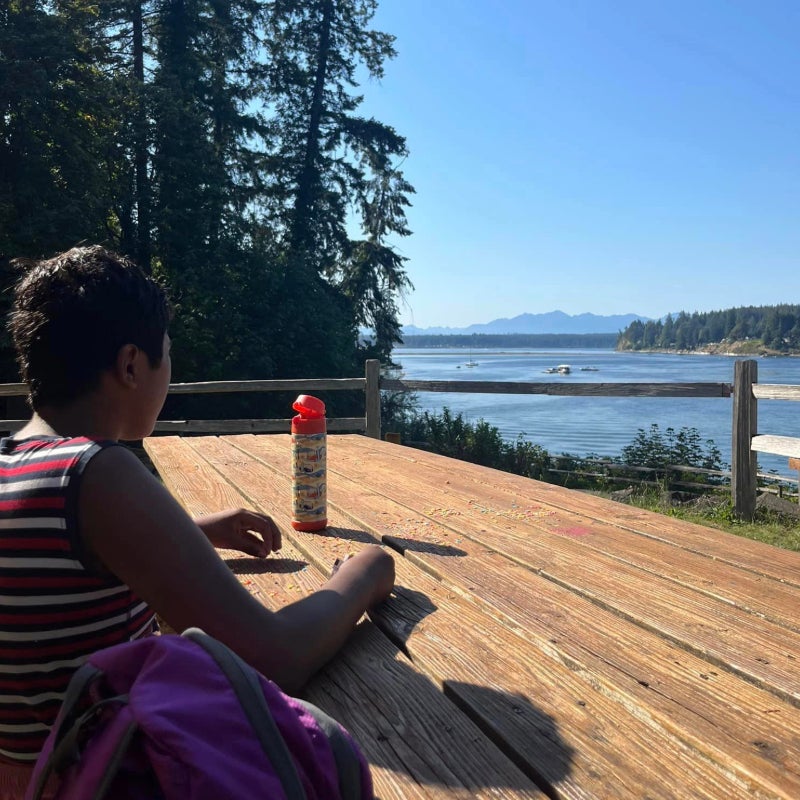 Jeeon sitting at a bench overlooking Vaughn Bay